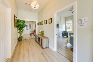 A spacious hallway with wooden flooring, a potted plant, a bench, and framed pictures on the wall. - Walk to Riverfront Park: Updated Home in Columbus! (Columbus)