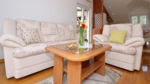 A living room with two sofas, a glass coffee table, and a wooden floor. - Bright Kaštela Apartment With Balcony and Private Parking (Kastela)