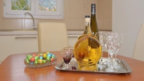 A dining table with a bottle of wine, glasses, and a bowl of colorful candies. - Bright Kaštela Apartment With Balcony and Private Parking (Kastela)