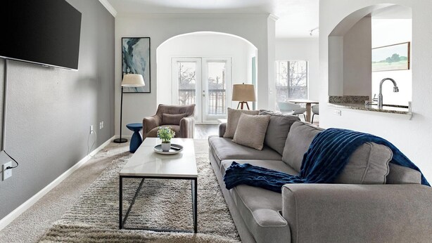 Un salon moderne avec un canapé, une table basse et un téléviseur fixé au mur.