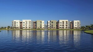 A modern apartment complex with a central water feature and a clear blue sky. - Landing | Stylish 2BD, Gym (Glendale)