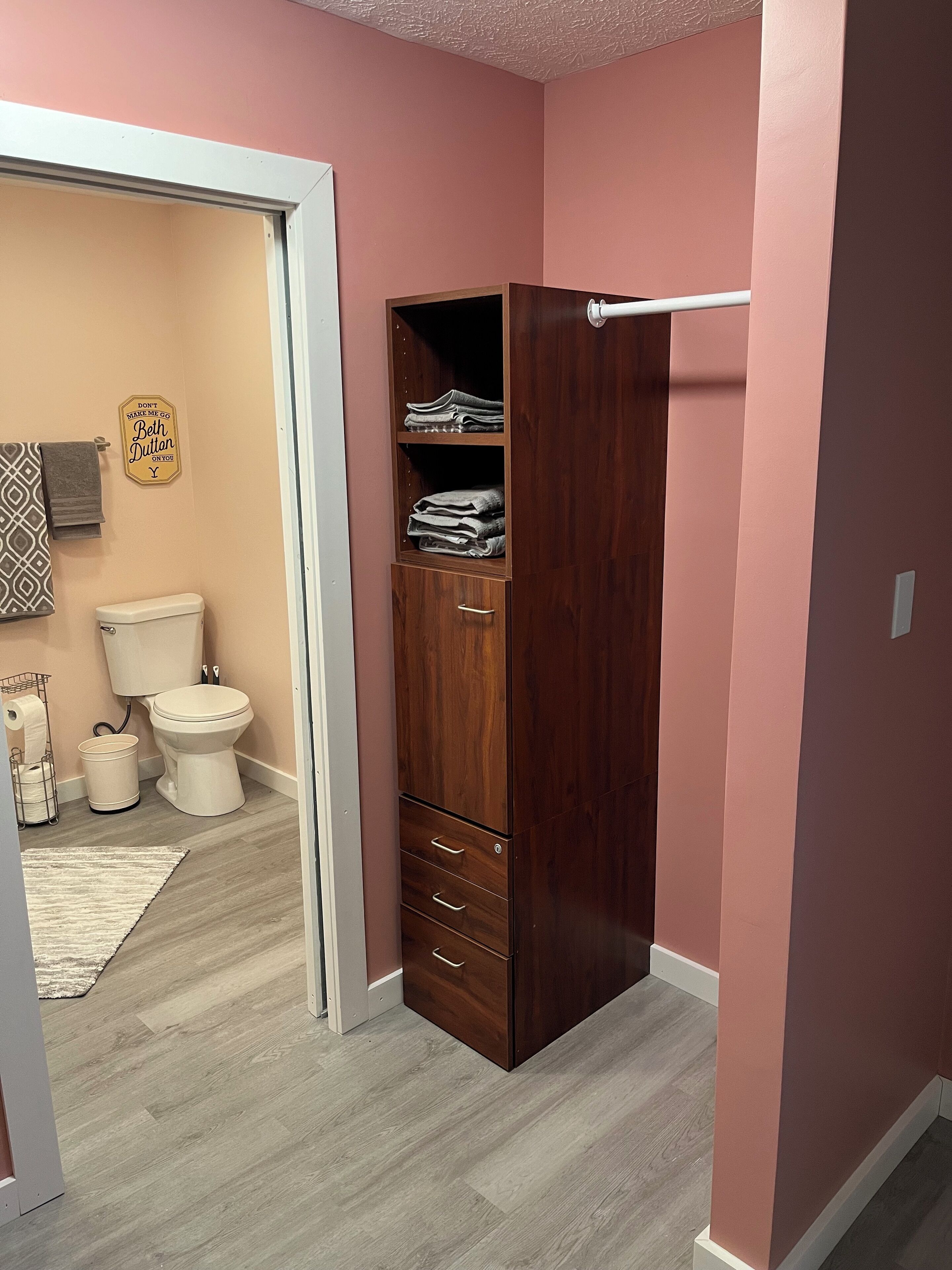 A bathroom with a wooden cabinet, a toilet, and a towel rack.