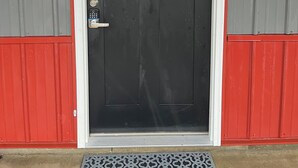 A black door with a frosted glass window above it, set in a grey and red wall.