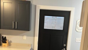 A kitchen with dark cabinets, a countertop, and a black door with a window.