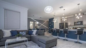 A modern living room with a sectional sofa, a coffee table, and a kitchen area with bar stools.