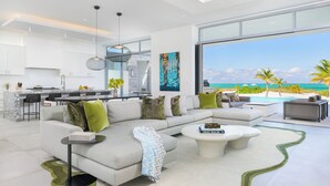 A modern living room with a large sofa, coffee table, and a view of the ocean.