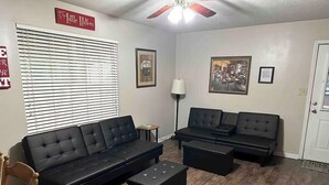 A living room with two black sofas, a coffee table, a lamp, and a framed picture on the wall.