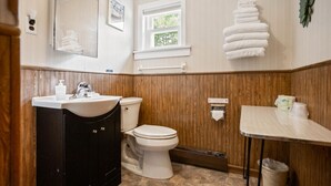Een badkamer met een houten wastafel, toilet, wastafel en handdoekrek.