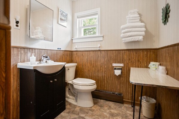 Une salle de bain avec un meuble-lavabo en bois, des toilettes, un lavabo et un porte-serviettes.
