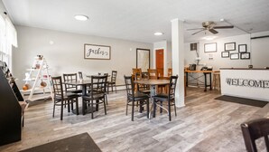 A spacious room with a dining area, a reception desk, and a ceiling fan. - Double Queen + Twin | Motel Suite Near Wellsboro (Wellsboro)