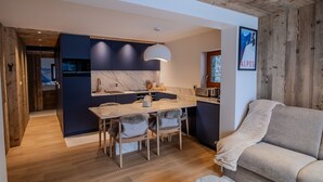 Une cuisine moderne dotée d’un plan de travail en marbre, de meubles en bois et d’un coin repas avec une table et des chaises.