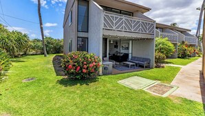 A modern two-story house with a patio area, a small garden, and a clear sky.