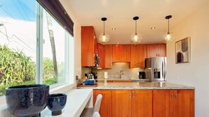 A modern kitchen with wooden cabinets, granite countertops, and stainless steel appliances.