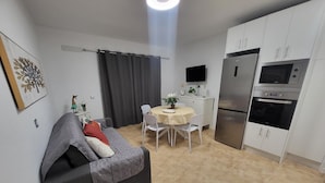 A compact living space with a sofa, dining table, and kitchenette.