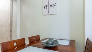 A dining table with a bowl of fruit, wooden chairs, and a wall with a 'relax' sign. - Studio 5min From Copacabana Beach Mvc901 (Rio de Janeiro)