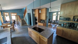 A modern kitchen with wooden cabinets, a built-in stove, and a dining area with a table and chairs. - Trout Lake Treehouse - A large, splendid, and private mountain home! (Trout Lake)