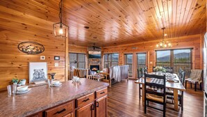 L’intérieur d’un chalet en bois comprend une cuisine, un coin repas et de grandes fenêtres.