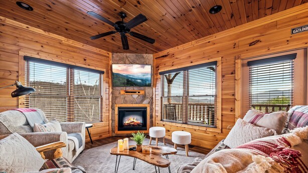 L’intérieur d’un chalet confortable, avec une cheminée, des murs en bois et de grandes fenêtres.