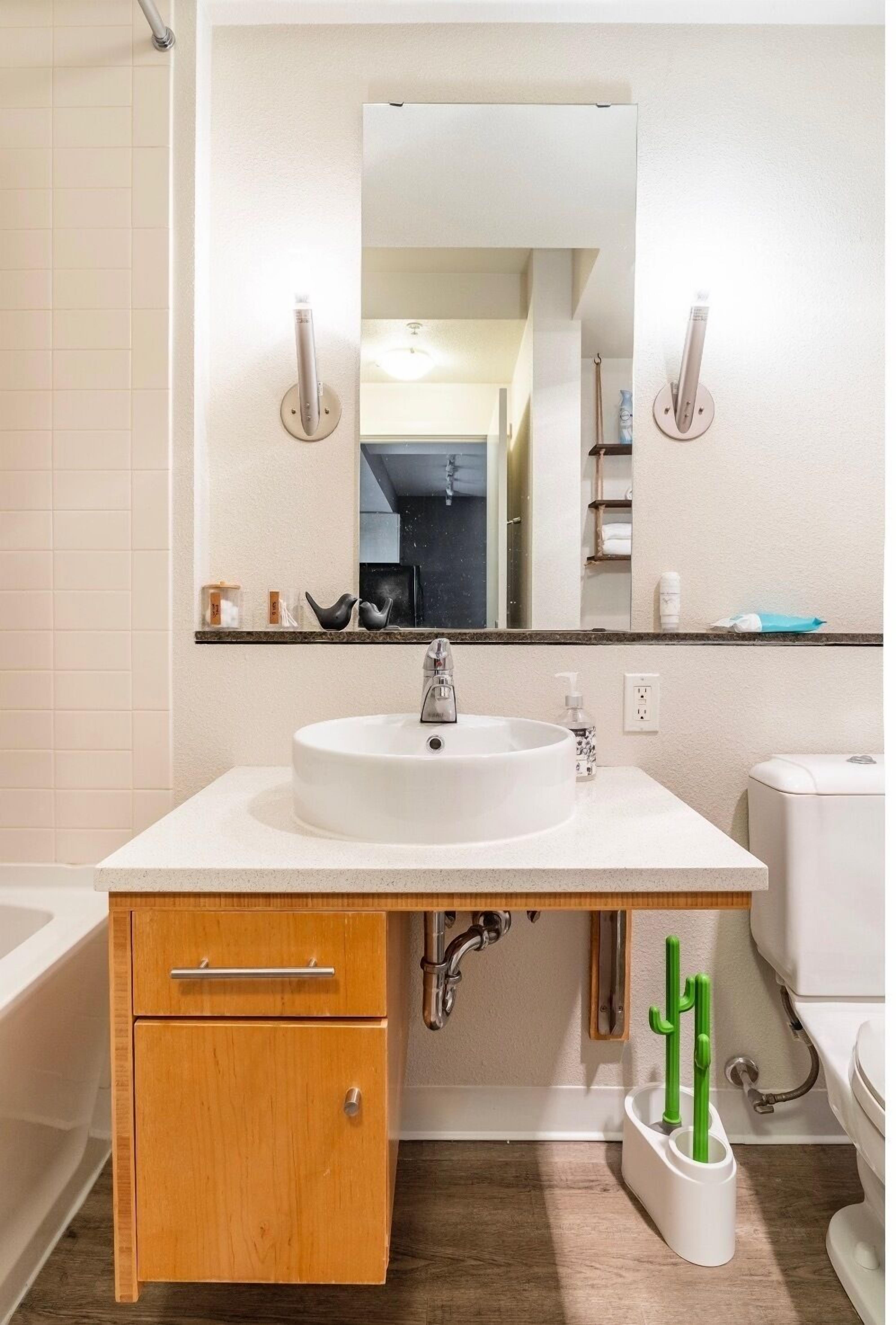 Une salle de bain avec un lavabo blanc, un meuble-lavabo en bois et un miroir au-dessus.