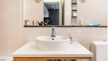 Une salle de bain avec un lavabo blanc, un meuble-lavabo en bois et un miroir au-dessus.