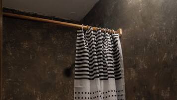 A bathroom with a striped shower curtain, a toilet, and a wooden towel rack.