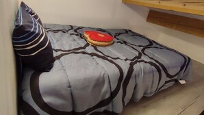 A small, narrow room with a bed, a pillow, and a red object on the bed. - L'Echappée du Camboux.  
Wellness discounts (Sainte-Cécile-d'Andorge)