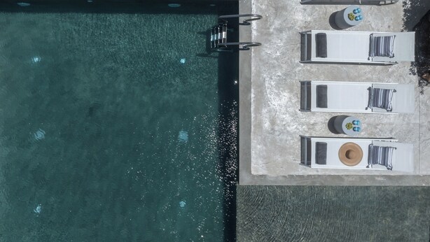 Luftaufnahme eines Schwimmbeckens mit vier Liegestühlen, einem kleinen Tisch mit Hut und einem Wasserspiel.