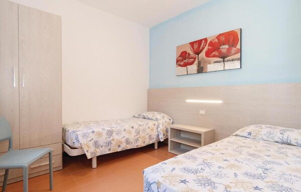 A room with two single beds, a wooden wardrobe, a small table, and a chair. - The Charming Marina Village Tipo 3-3 Bedroom Villa 6 Persons (Comacchio)