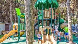 A playground with slides and climbing structures surrounded by trees.