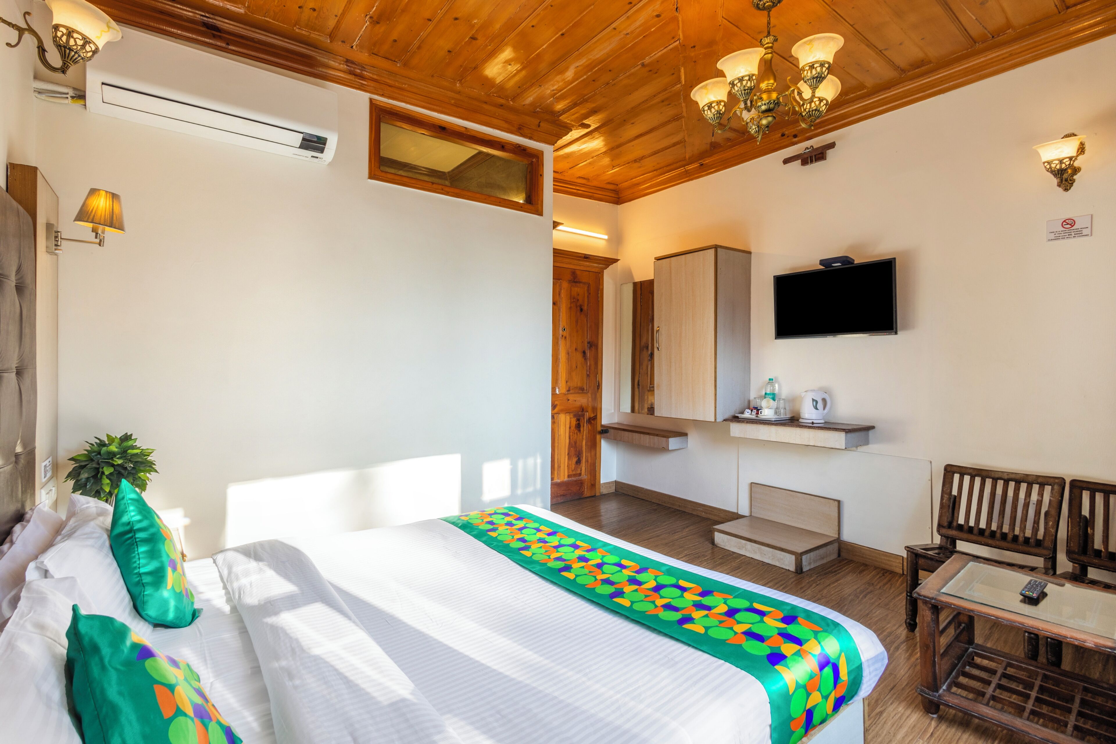 Una habitación de hotel con una cama, un televisor, una mesita y una silla.