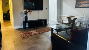 Un salon moderne avec un téléviseur à écran plat, une table à manger en verre et un canapé.