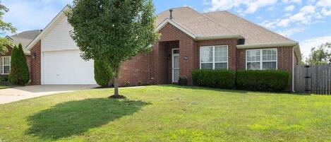A residential house with a garage, a well-maintained lawn, and a wooden fence.