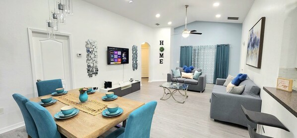 Una sala de estar moderna con un sofá gris, una mesa de centro y un televisor montado en la pared.