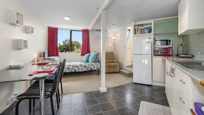 Un espace de vie compact comprenant un coin repas, une kitchenette et un lit avec vue.