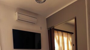 A living room with a flat-screen TV mounted on the wall, a sofa, a small table with a decorative item, and a potted plant. - A lo de Pepa - Full house, temporary family rental, in the Uco Valley (Tupungato)