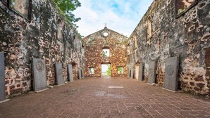 A courtyard with a central building featuring a dome and arched windows, surrounded by stone walls and tombstones. - Aira Hotel Melaka (Malacca City)
