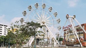 A Ferris wheel with a water body in the foreground and a building with 'Dixie Side' signage in the background. - Aira Hotel Melaka (Malacca City)