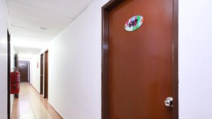 A corridor with a fire extinguisher, a door with a number sign, and a tiled floor. - Aira Hotel Melaka (Malacca City)