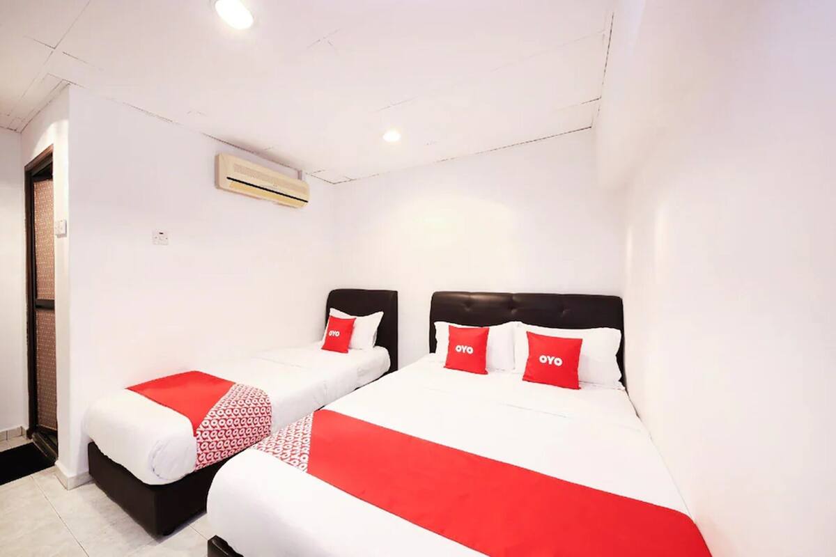 A hotel room with two beds, each with a red and white bedspread and matching pillows.