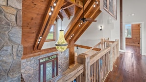 Ein Holzinnenraum mit einer Steinwand, einer Holztreppe und einer hängenden Leuchte.