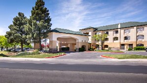 A multi-story hotel with a central courtyard, featuring a large tree and a well-maintained lawn. - CASH REWARDS INN & SUITES (Roswell)