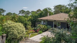 Una casa con tetto in tegole, circondata da rigogliosa vegetazione e un patio in legno.