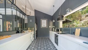 Una cucina moderna con pavimento a motivi bianchi e neri, mobili bianchi e illuminazione a sospensione.