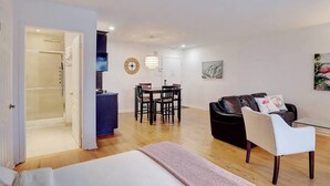 A modern apartment with a dining area, a living room with a sofa and a coffee table, and a walk-in closet.
