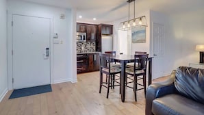 Una cocina moderna con armarios de madera oscura, un microondas y un comedor con mesa y sillas.