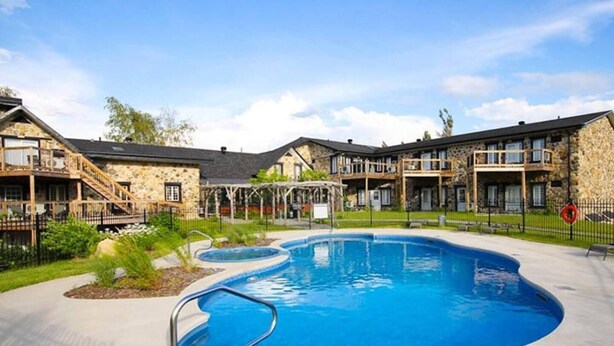 Un complejo residencial con piscina, edificios de piedra y un área exterior cercada.