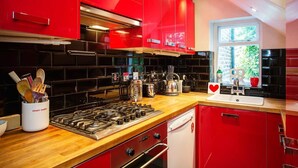 Een moderne keuken met rode kastjes, een gasfornuis en een raam met uitzicht op groen.
