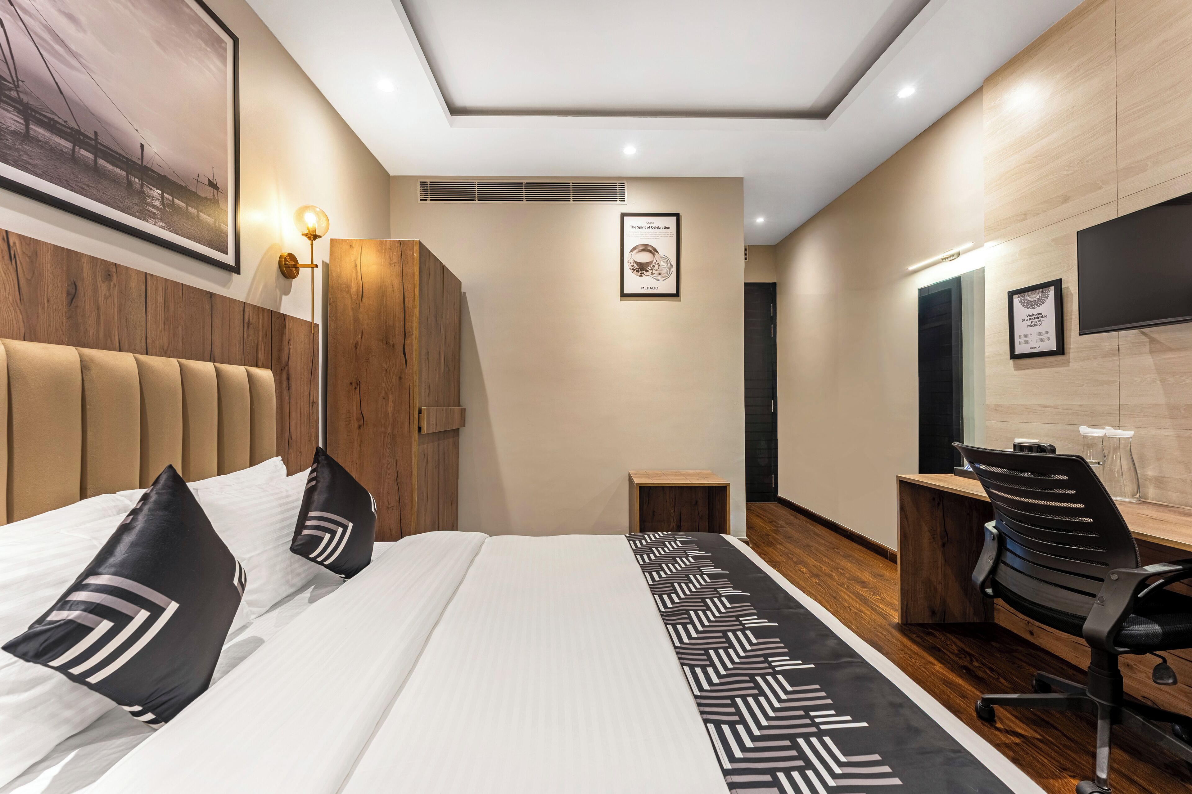 Ein modernes Hotelzimmer mit einem großen Bett, einem Schreibtisch, einem Stuhl und einem Fernseher.
