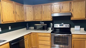 A kitchen with wooden cabinets, a microwave, a toaster, a coffee maker, and a stove.