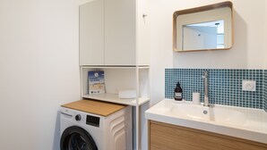 Un bagno compatto con lavatrice, lavandino e specchio, e una parete rivestita in piastrelle blu.